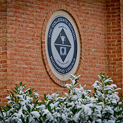 The Collegiate School insignia on a wall. Links to Gifts by Estate Note